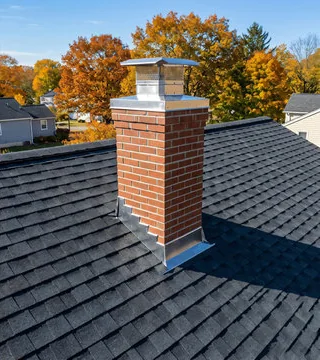After: new red brick chimney with stainless cap and fresh flashing on a dark roof